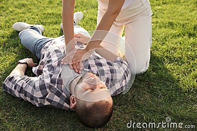 Woman doing cardiac massage to unconscious man with heart attack on green lawn Stock Photo