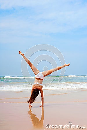 Woman doing cartwheel at the beach Stock Photo