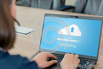 Woman doing cloud uploading on laptop in office Stock Photo