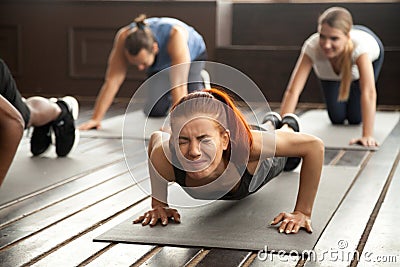 Woman doing difficult plank exercise or pushups at group trainin Stock Photo