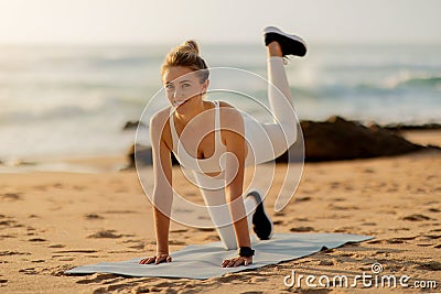 Woman doing exercises for butts on sunset beach Stock Photo