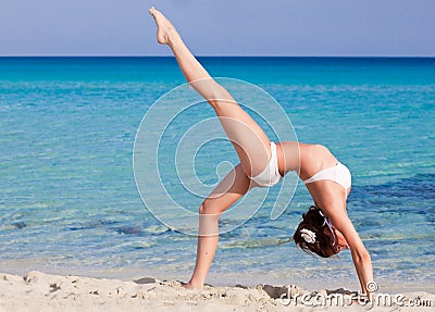 Woman is doing flexibility exercise on the beach Stock Photo