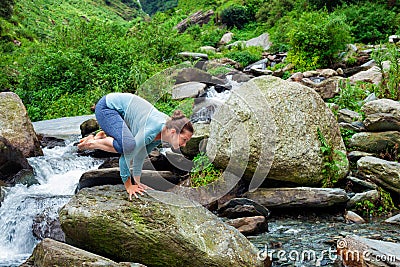 Woman doing Kakasana asana arm balance outdoors Stock Photo