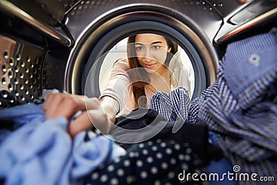 Woman Doing Laundry Reaching Inside Washing Machine Stock Photo