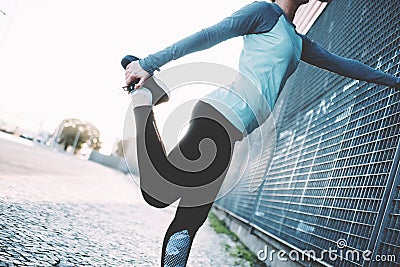 Woman doing legs warming exercise on the street, safety stretch before urban workout Stock Photo