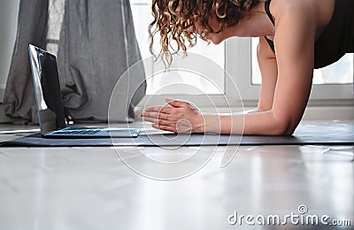 Woman doing plank pose at home during online training Stock Photo