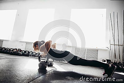 Woman doing push-ups exercises on kettlebells. Cross fit training Stock Photo