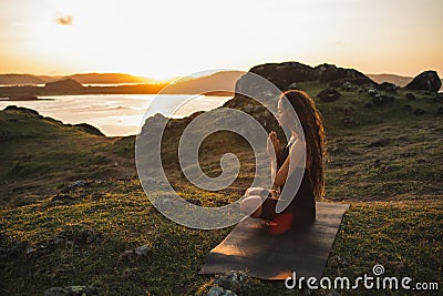 Woman doing yoga alone at sunrise with mountain view. Harmony with nature Stock Photo