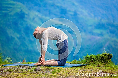 Woman doing yoga asana Ustrasana camel pose outdoors Stock Photo