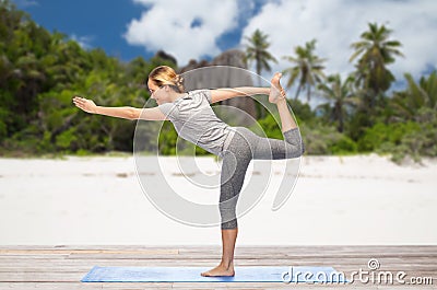 Woman doing yoga lord of the dance pose on beach Stock Photo