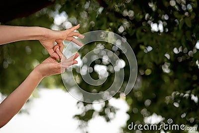 Woman doing yoga mudra of hand meditation and relaxes against the backdrop of greenery and sunset. Stock Photo