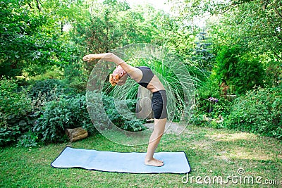 Woman doing yoga in the park, young girl doing various wellness exercises Stock Photo