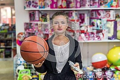 Woman with dollar banknotes and orange ball in toy shop Stock Photo