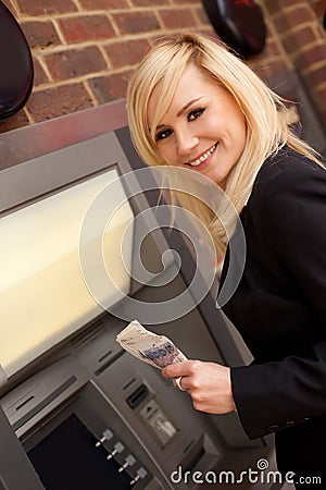 Woman drawing cash at an ATM Stock Photo