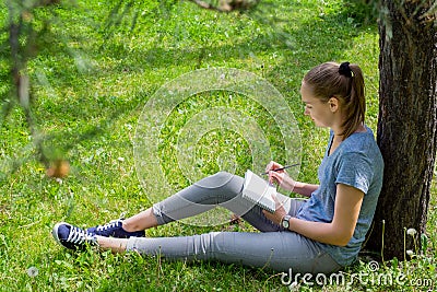 Woman draws sitting on grass Stock Photo