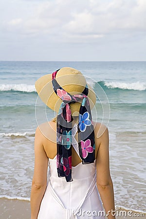 A woman with dress and hat on the beach Stock Photo