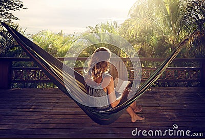 Woman in a dress reading book in a hammock in the jungle at suns Stock Photo