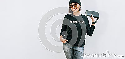 Woman dressed black outfit with bright accessories stands near w Stock Photo