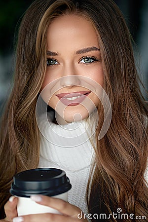 woman drinking coffee. Girl holds paper cup of hot latte. Stock Photo