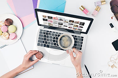 top view of woman drinking coffee with macaroon while using laptop Editorial Stock Photo