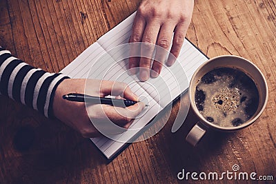 Woman drinking coffee and writing a diary note Stock Photo