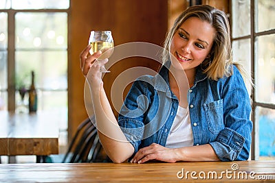 A woman drinking fresh craft cider from the tap, holding up her glass to cheers her friends at the bar Stock Photo