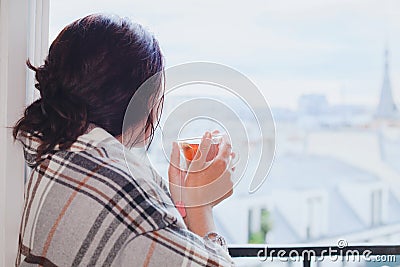 Woman drinking hot tea and looking at the window, cozy winter at home Stock Photo