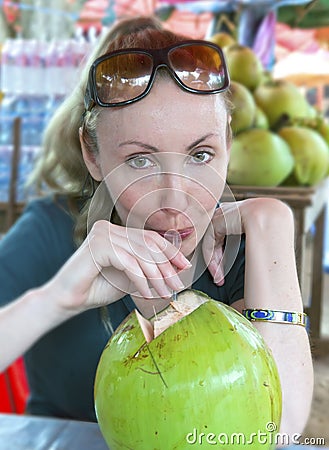 Woman drinks coconut milk from a big green coco Stock Photo