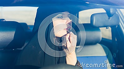 Woman driver paints lips in the car looks in the mirror Stock Photo