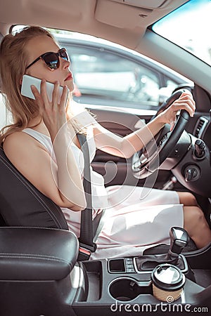 Woman driving car in dress, stands in parking lot, looks in rearview mirror, makes phone calls and listens voice Stock Photo