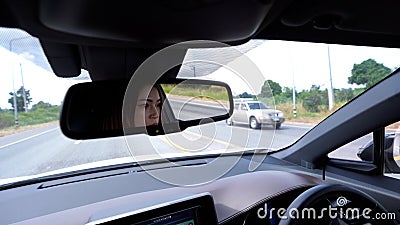 Woman driving car reflects in rear view mirror Stock Photo