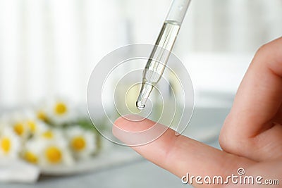 Woman dropping essential oil on finger over table Stock Photo