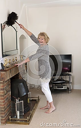 Woman dusting a mirror above the fireplace Stock Photo