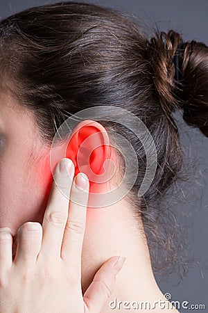 Woman with earache, ear pain on gray background Stock Photo