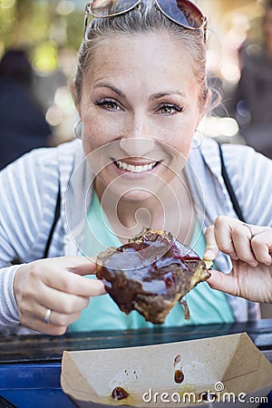 Woman eating barbecue pork ribs at an outdoor eatery Stock Photo