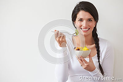 Woman Eating Bowl Of Fresh Fruit Against White Background Stock Photo