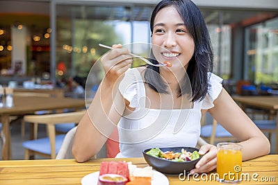 Woman eating Breakfast. Fruits such as watermelon, papaya, melon, passion fruit, orange juice and coffee. placed on a gray Stock Photo