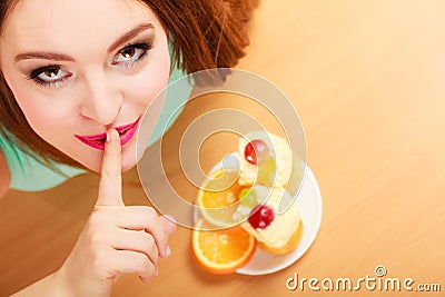 Woman eating cake showing quiet sign. Gluttony. Stock Photo