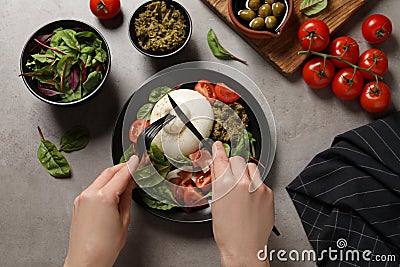 Woman eating delicious burrata salad at grey table, top view Stock Photo