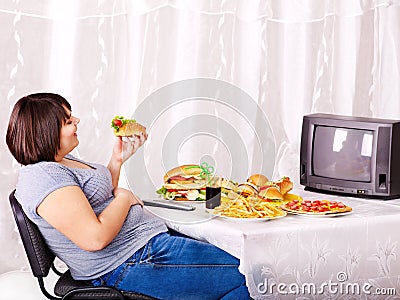 Woman eating fast food and watching TV. Stock Photo