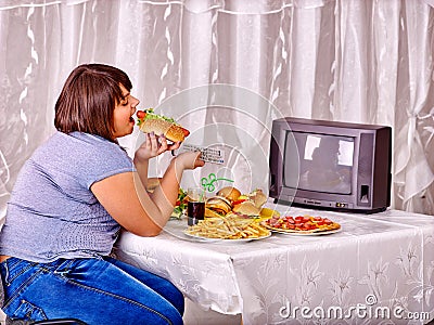 Woman eating fast food and watching TV Stock Photo