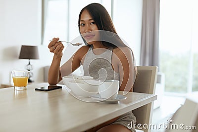 Woman eating healthy breakfast at home in morning at table Stock Photo