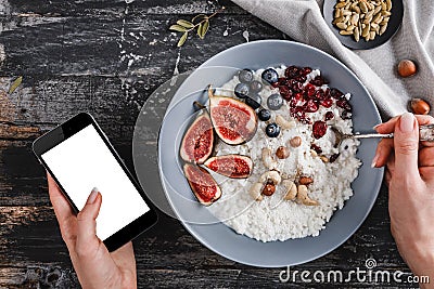 Woman eating the Rice coconut porridge with figs and nuts in plate and pointing finger on screen smartphone Stock Photo