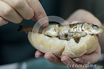 Woman eating roasted sardines with her hands Stock Photo