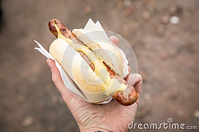 Woman eating typical grilled German Bratwurst sausage street food with bread roll bun and mustard on the go Stock Photo