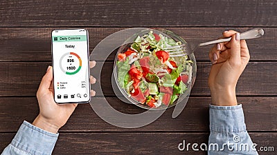Woman eating vegetable salad and counting calories on mobile application Stock Photo