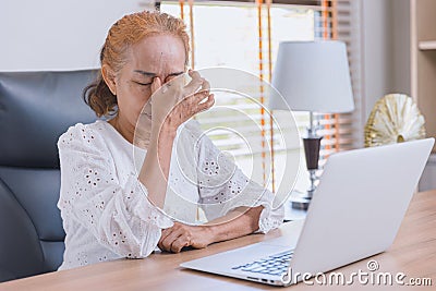 Woman elderly eyes pain from Asthenopia stress tired sinus suffer fatigue from hard work with computer screen Stock Photo