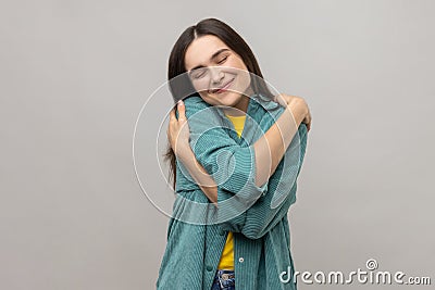 Woman embracing herself and smiling with expression of pleasure, being selfish and narcissistic. Stock Photo