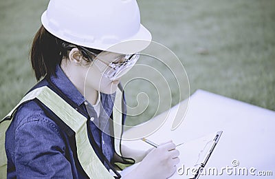 Woman engineer or architecture checking chack list or inspection data in clipboard by ware personal protective equipent ppe at Stock Photo