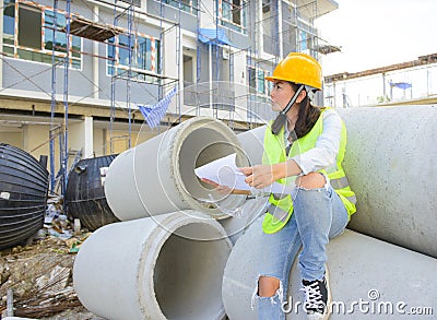 Woman engineers holding blueprint at construction site Stock Photo